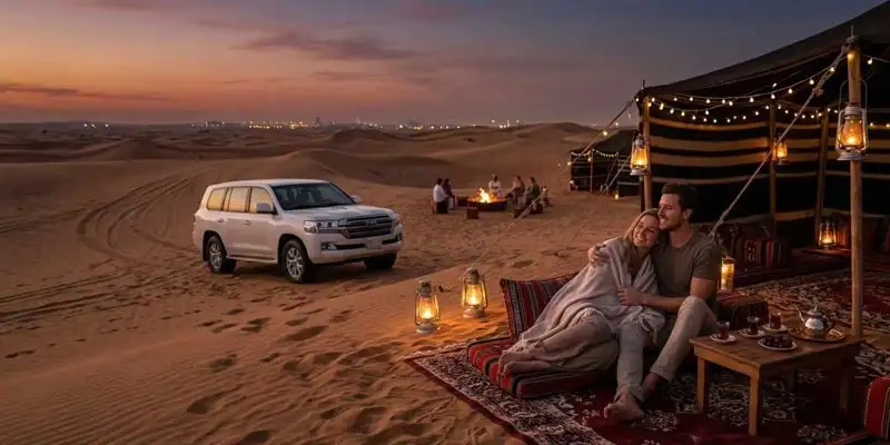 Under a twilight sky, a couple relaxes by their lit desert camp with a 4x4 vehicle parked nearby and Jeddah’s city lights on the horizon—a highlight among intimate experiences for partners visiting Jeddah.