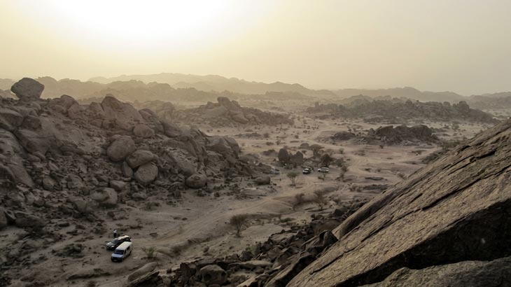 Scenic view of New Moon Valley desert landscape with tour vehicles from Jeddah at sunset.