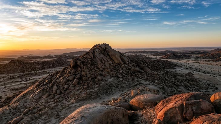 Group of visitors on the summit of New Moon Valley rock formation at golden hour from Jeddah.